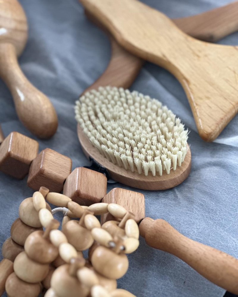 Nature morte des outils de madérothérapie : planche, brosse, rouleaux et cloche de bois