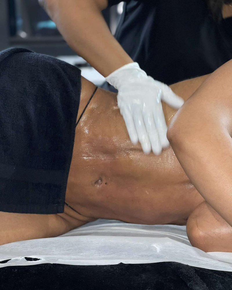 Drainage lymphatique manuel sur l'abdomen d'une cliente, gants blancs et drapé noir