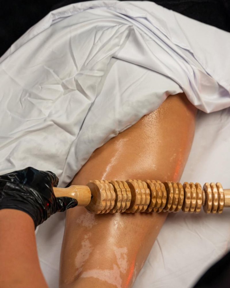 Rouleau de bois cannelé passé sur la cuisse pendant une séance de madérothérapie